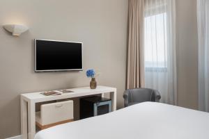 a hotel room with a bed and a tv on a wall at NH Ancona in Ancona