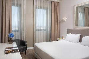 a hotel room with a white bed and a table and a window at NH Ancona in Ancona +26 photos