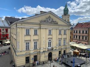 a large yellow building with a clock tower on top at Apartamenty Magdalena in Lublin