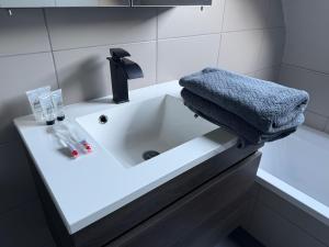 a white bathroom sink with a towel on it at Modern Duplex Apartment with terrace view in Stekene +3 photos
