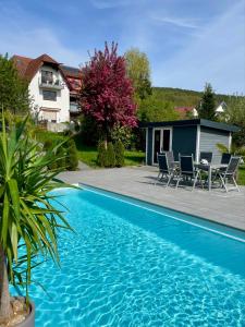 a blue swimming pool with chairs and a table at Pension Höchemer in Bad Bocklet