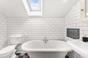 a white bathroom with a toilet and a bath tub at Seafront Duplex Worthing Beach - Sea Views 8 Guests in Worthing +44 photos
