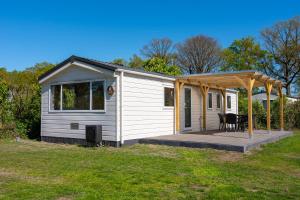 a tiny house with a porch and a deck at Recreatiepark Goorzicht in Aalten +10 photos