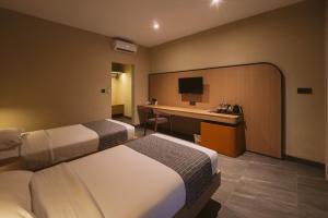 a hotel room with two beds and a desk at Legong Keraton Beach Hotel in Canggu