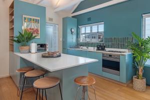 a blue kitchen with a counter and stools at Cosy Cottage Onrus - With Pool in Hermanus +17 photos