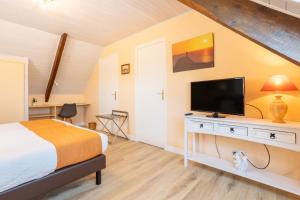 a bedroom with a bed and a flat screen tv at Chambres D'hôtes De Kerantum in Mahalon