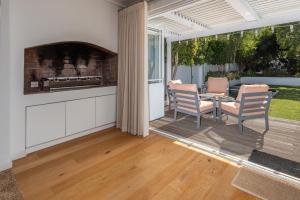 a patio with two chairs and a table with a fireplace at Cosy Cottage Onrus - With Pool in Hermanus