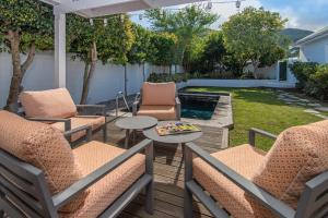 a patio with chairs and tables and a pool at Cosy Cottage Onrus - With Pool in Hermanus