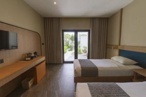 a hotel room with two beds and a television at Legong Keraton Beach Hotel in Canggu