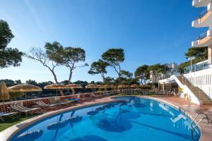 a pool at a hotel with chairs and umbrellas at Cabot Cala Ferrera in Cala d´Or