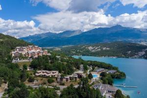a resort on a hill next to a body of water at Mobile homes for 4 people with lake view in Residence L'Ecrin du Lac, Chorges in Chorges