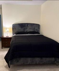 a bedroom with a bed with a black comforter at Joykip's place in West Des Moines