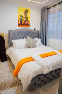 a bedroom with a large bed with an orange blanket at LIBERTY TOWERs in Lower Kabete