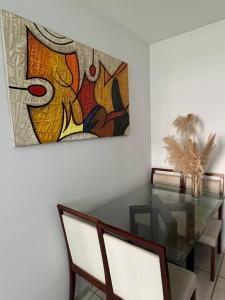 a dining room with a glass table and a painting at Excellent value for money - Fully equipped apartment in Macaé
