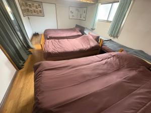 three beds are lined up in a room at 一棟貸しの宿 餓鬼大将と別館トキワ荘 in Omachi