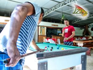 two men playing a game of pool with a cue at Pousada Recanto Iza in Alfredo Chaves