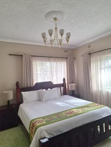 a bedroom with a large bed with a chandelier at Eastview Guest House in Harare +44 photos