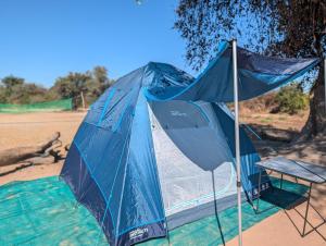 a blue tent and a chair on the beach at Muke Village Guest House in Livingstone