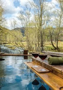 two glasses of wine sitting on a table next to a swimming pool at Cabana de la rau Satic in Sătic