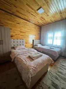 two beds in a room with a wooden wall at Ertunç Turizm in Kahramanmaraş
