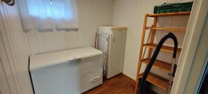 a small kitchen with a white refrigerator and a shelf at Apartment Solbakken Feriehus in Fevåg +22 photos