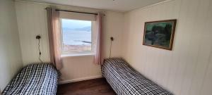 two beds in a room with a window at Apartment Solbakken Feriehus in Fevåg