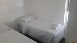 a small room with two beds with white sheets at Double Kit 404 - 2 Quartos Perto UNB in Brasilia