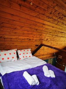 a bed in a room with a purple blanket and pillows at Kazbegi Mountain Cottage MTA-Shi in Kazbegi