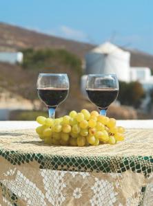 two glasses of wine sitting on a table with grapes at Irene Rooms in Chora Folegandros