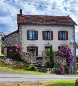 a stone house with wooden shuttered windows and flowers at La maison du Mas Rando in Saint-Georges-Nigremont +8 photos