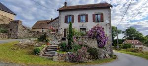 a stone house with flowers on the side of a road at La maison du Mas Rando in Saint-Georges-Nigremont