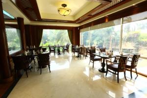 a dining room with tables and chairs and large windows at Avari Towers Karachi in Karachi