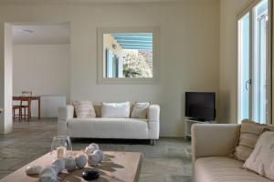 a living room with two white couches and a tv at Sea Breeze in Otziás