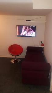 a living room with a red stool and a television at Double Kit 404 - 2 Quartos Perto UNB in Brasilia