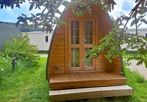 a wooden cabin with a window in the grass at Camp Diekirch - Camping Pod in Gilsdorf +5 photos