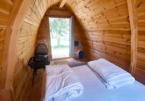 a bed in a wooden room with a window at Camp Diekirch - Camping Pod in Gilsdorf