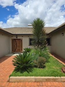 a house with a palm tree in front of it at Ivory & Mane Estate - Jacaranda in Harare