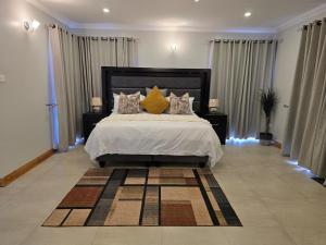 a bedroom with a large bed with pillows on it at Ivory & Mane Estate - Jacaranda in Harare +13 photos