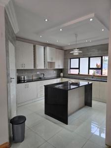a large kitchen with a black island in the middle at Ivory & Mane Estate - Jacaranda in Harare
