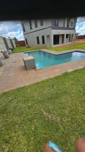a swimming pool in front of a house at Ivory & Mane Estate - Jacaranda in Harare