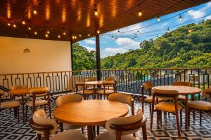 a restaurant with tables and chairs on a balcony at The JJ Corbett Bliss, Sitabani A River Access Wildlife Resort in Amgarhi