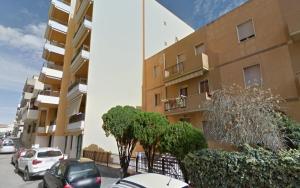 un bâtiment avec des voitures garées dans un parking dans l'établissement Alguer 46, à Alghero