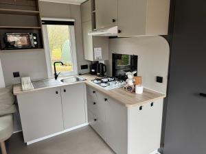 a small kitchen with white cabinets and a sink at Camp Diekirch - Mobilehome Plus 6 pers in Gilsdorf +2 photos