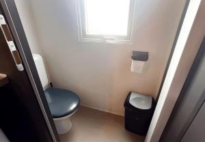 a small bathroom with a blue toilet and a window at Camp Diekirch - Mobilehome Plus 4p in Gilsdorf