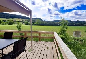 a deck with a table and chairs and a view of a field at Camp Diekirch - Mobilehome Plus 4p in Gilsdorf