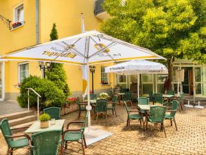 an outdoor patio with tables and chairs and an umbrella at Hotel Panorama Nickenich in Nickenich