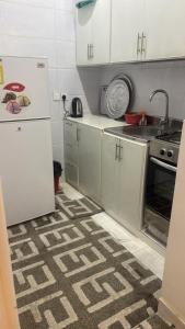 a kitchen with white cabinets and a white refrigerator at شقة فاخرة بغرفتين نوم وصالة ومجلس in Abha