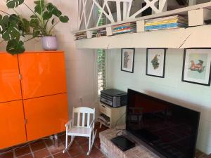 a living room with an orange cabinet and a television at Chalet cosy - terrasse et détente, escapade nature au Bonsoy in Waulsort