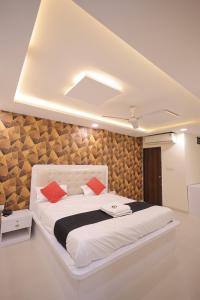 a bedroom with a large white bed with red pillows at Hotel Venus Inn in Indore