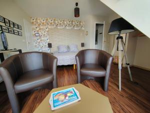 a living room with two chairs and a bed at LE RUBAN BLEU FACE A LA MER in Arromanches-les-Bains
